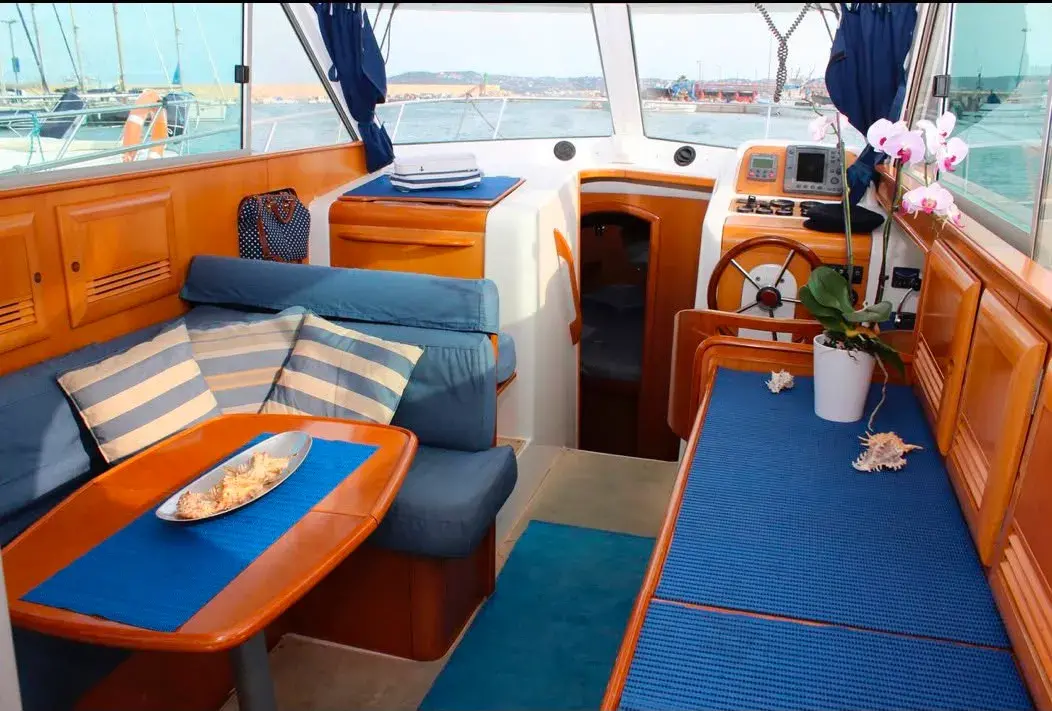 Salón interior del barco con sofá azul y acabados en teca
